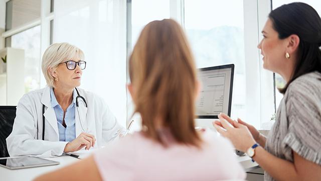 A patient with her interpreter conversing with a physician